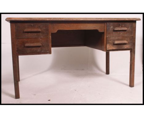 A 1930's to mid century oak twin pedestal air ministry style desk having a twin bank of drawers divided by a central recess. 