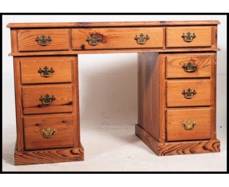 An antique style country pine twin pedestal office desk. Each pedestal raised on plinth bases with a series of drawers having