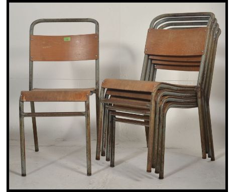 A stack of vintage mid century tubular metal and ply wood Industrial stacking chairs bearing original light green paint.  Mea