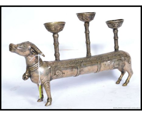 A 20th century white metal Indian elongated cow candlestick holder. 37cms long
