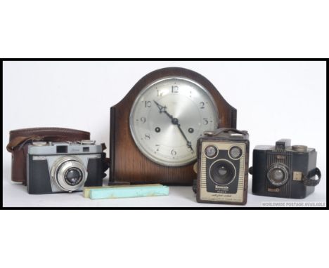 A mid 20th century eight day mantle clock along with a vintage Iloca camera, vintage Kodak cameras and a clinical thermometer
