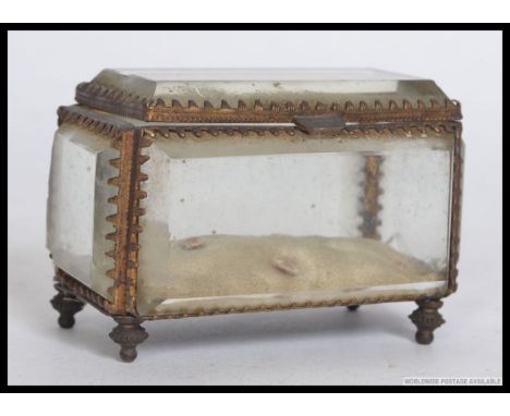 A 20th century bevelled glass casket having gilt metal rococo mount frame being raised on finial feet. Pin cushion inside wit
