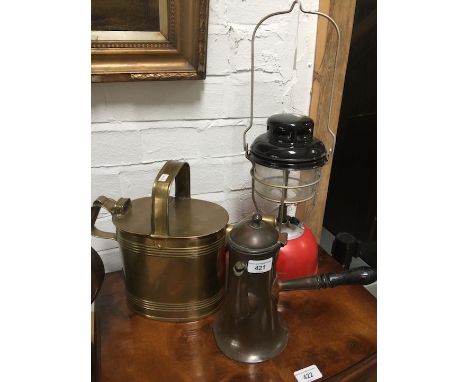 A mixed lot comprising a brass watering can, a copper chocolate pot with ebonised handle and a Tilley lamp. 