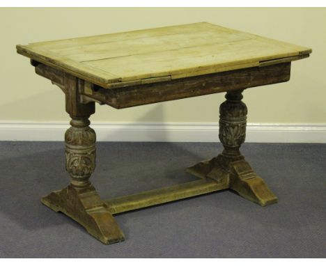 A George V oak drawleaf dining table, the rectangular top raised on turned and carved baluster supports with bracket feet uni