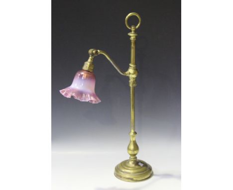 A late 19th/early 20th century gilt brass adjustable table lamp, fitted with a pink vaseline glass shade, raised on a circula