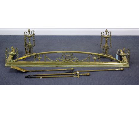 An Edwardian brass fender, width 135cm, a pair of brass fire dogs and a set of three brass fire tools.