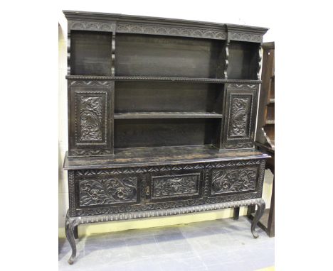 A late Victorian stained oak dresser with carved decoration, the shelf back fitted with two cupboards above three further cup