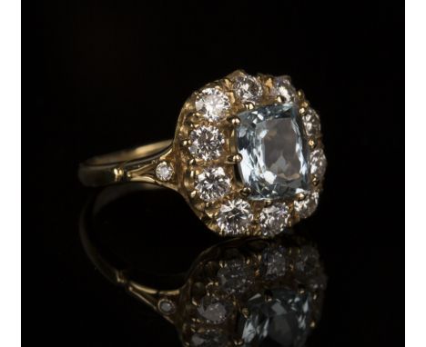 An 18ct gold, aquamarine and diamond cluster ring, claw set with a curved rectangular cut aquamarine within a surround of ten