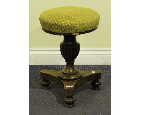 A Victorian rosewood revolving piano stool, the upholstered seat raised on a reeded baluster column and triform base with tur