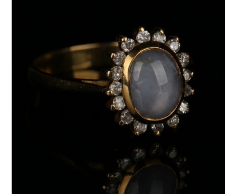 A gold, diamond and star sapphire oval cluster ring, mounted with the star sapphire within a surround of circular cut diamond