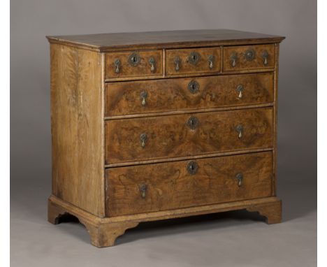 A George I walnut chest of three short and three long drawers, the crossbanded top above feather banded drawers, raised on br
