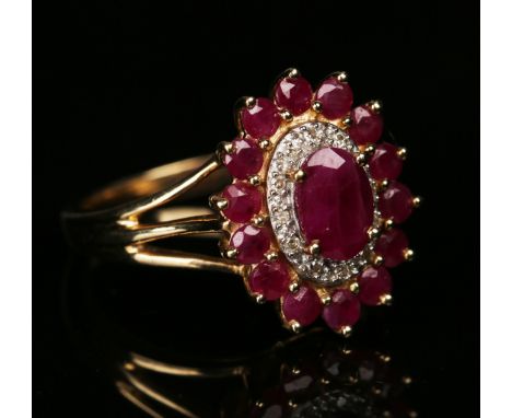 A 9ct gold, ruby and diamond oval cluster ring, claw set with the principal oval cut ruby within a surround of circular cut d