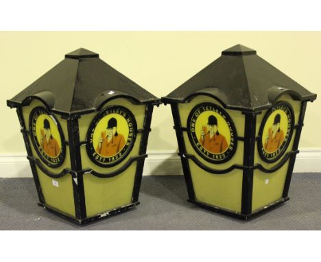 A pair of mid-20th century advertising wall mounted street lights of tapering square section, the black painted metal frames 