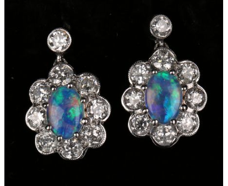 A pair of 18ct white gold, opal and diamond pendant cluster earrings, each claw set with an oval opal within a surround of ci