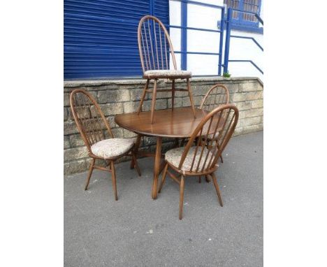 A Ercol oak oval drop-leaf table and four high hooped back dining chairs. 