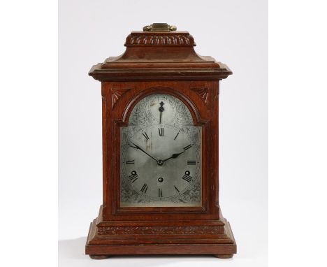 Oak musical bracket clock, the brass handle above a gadrooned and down-swept pediment, the arched glazed door opening to reve