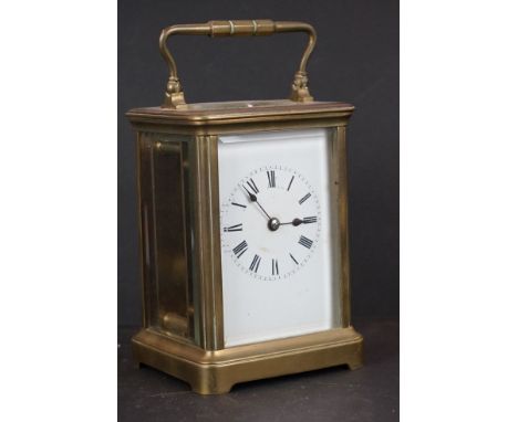 A vintage brass cased carriage clock with beveled glass panels and white enamel dial. 