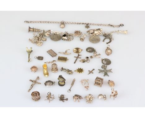 A collection of white metal and yellow metal charms together with a silver charm bracelet. 