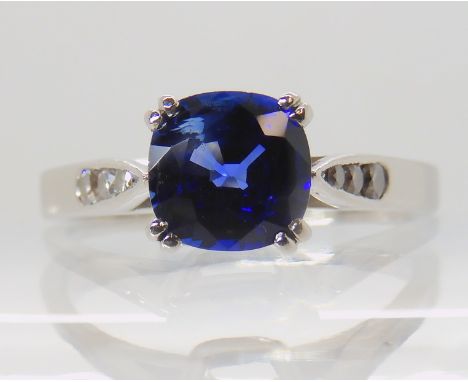 A PLATINUM SAPPHIRE AND DIAMOND RING by Glasgow goldsmith Alan P. Fulton. The central cushion cut sapphire is approx 6mm x 6.