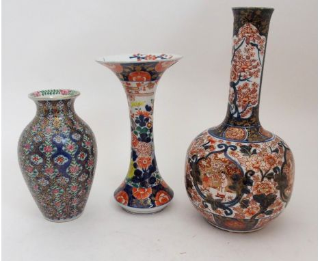 AN IMARI BOTTLE SHAPED VASE painted with figures in gardens surrounded by foliage and detailed in gilt, signed, 40cm high, a 