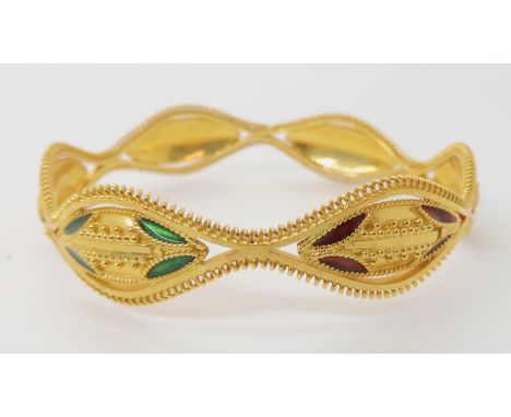 A BRIGHT YELLOW METAL DECORATIVE BANGLE with red and green enamel and granulation detail, stamped 22c to the interior.  Inner