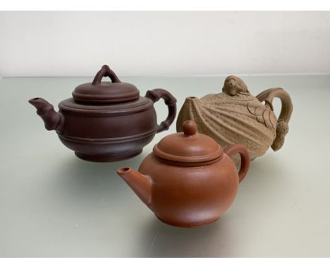 A group of Chinese Yixing teapots comprising: a ribbed example, the cover with mouse or rat finial, the handle modelled with 