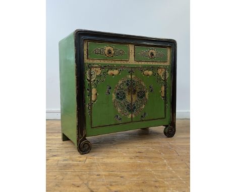 A Chinese green lacquered cabinet, two drawers over two cupboards opening to a shelf behind, the front of all over floral des