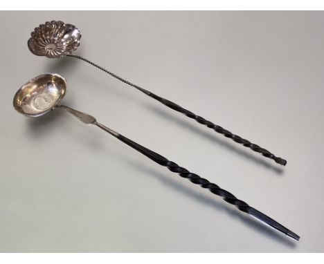 A George III white metal toddy ladle, c. 1800, with coin-inset oval bowl on a balleen twist handle; together with a Continent