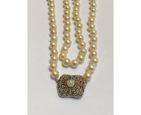 A single strand pearl and diamond necklace, the uniform strand of cultured pearls on a white metal plaque clasp millegrain se