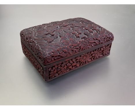 A Chinese cinnabar lacquer box and cover, of rectangular form, the slightly domed cover carved in relief with figures and bui