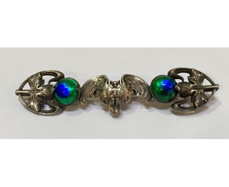 An Art Nouveau white metal and enamel brooch, modelled with an owl, it's wings outspread between a pair of blue/green enamel 