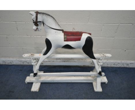 A BLACK AND WHITE PAINTED WOODEN ROCKING HORSE, with oxblood leather seat, and  brown leather reigns, length 133cm x depth 42