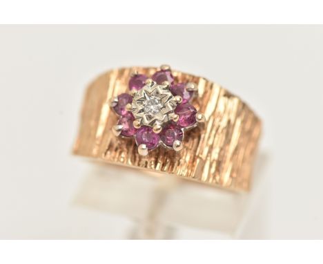 A 9CT GOLD RUBY AND DIAMOND CLUSTER RING, set with a flower cluster of eight small circular cut rubies, with a central illusi