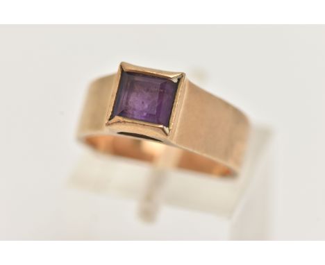 A 9CT GOLD AMETHYST RING, set with a square cut amethyst collet set to the wide polished band, hallmarked 9ct London, ring si
