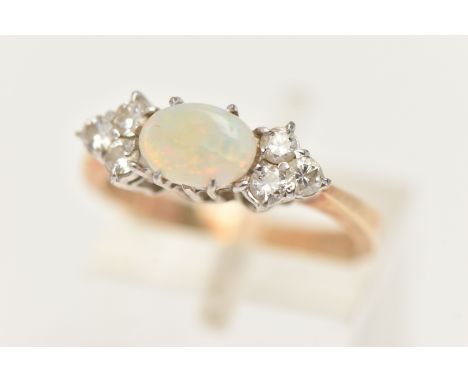 A 9CT GOLD OPAL AND DIAMOND RING, set with a central oval cut opal cabochon, four claw set and flanked with six round brillia