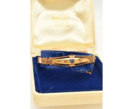A VICTORIAN YELLOW METAL GEM SET BANGLE, with a star set circular cut blue sapphire, flanked with two star set single cut dia