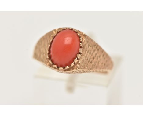 A 9CT GOLD CORAL RING, set with an oval coral cabochon, claw set to the bark effect shoulders and polished band, hallmarked 9