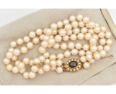 A DOUBLE STRAND CULTURED PEARL NECKLACE WITH YELLOW METAL GARNET SET CLASP, two rows of individually knotted cultured cream p