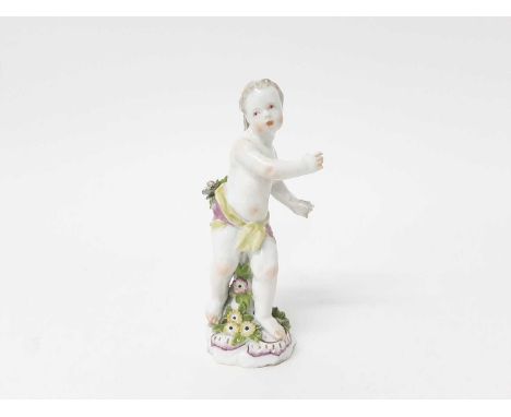 A Chelsea figure of a putto, circa 1756, shown standing on a scrollwork base with applied flowers, 14.75cm tallCondition repo