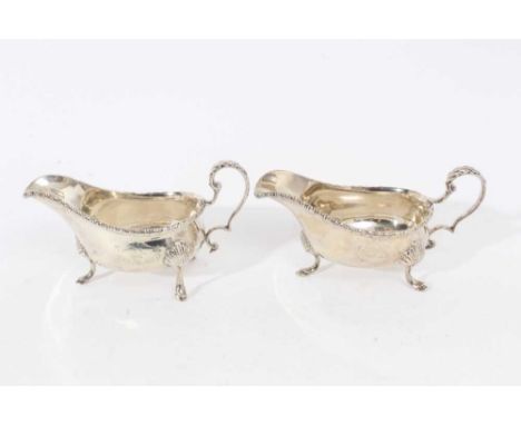 Pair of late Victorian silver sauce boats of helmet form, with scroll handles, gadrooned borders and engraved armorials, each