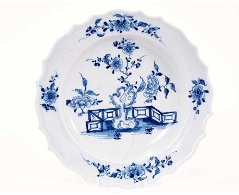 Lowestoft plate, with thickened and shaped rim, painted in blue with flowers and rockwork within a fenced garden, sprigs in t