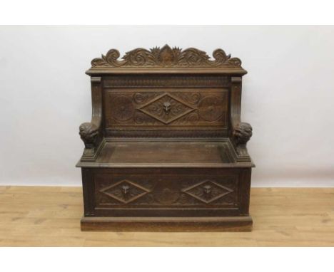 Victorian carved oak bench, with panel back centred by carved mask and box base with hinged seat, flanking carved lion arms, 
