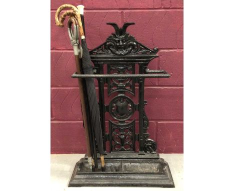 Victorian cast iron stick stand, black painted with pierced mask ornament, 93cm high with a shooting stick, ivory topped cane