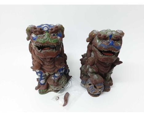 Pair of large Japanese pottery dog of Fo ornaments, each shown resting a paw on a ball, 31.5cm and 33.5cm tall