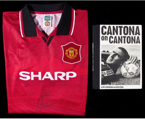 Eric Cantona signed football shirt and book,
a red replica Manchester United jersey signed in black marker pen; and a signed 