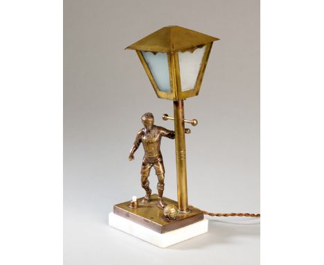 A table lamp designed with a brass footballer set on a marble base,
the lamp post with detachable hood, fitted for electricit