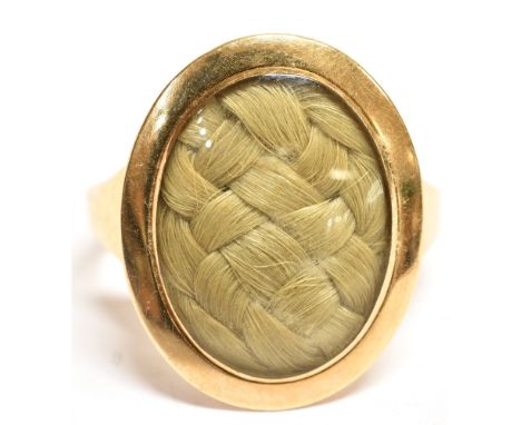 A GEORGIAN MOURNING RING  the signet style ring with oval head glazed compartment containing plaited hair, the reverse engrav