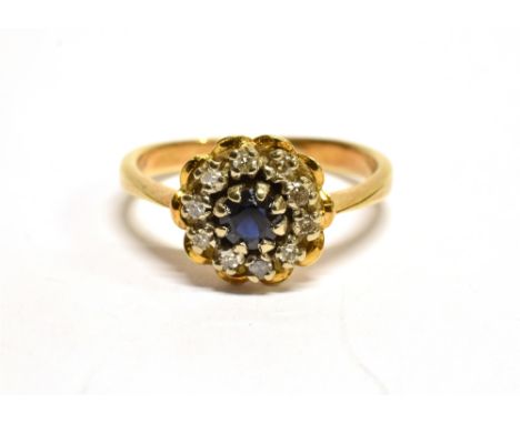 AN 18 CARAT GOLD SAPPHIRE AND DIAMOND ROUND CLUSTER RING  the round cut blue sapphire approx. 4mm diameter, surround of small