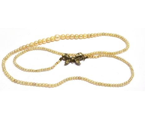 A SINGLE ROW PEARL NECKLACE  with a silver paste set ribbon bow clasp, the pearls graduating from approx. 5.5mm baroque shape