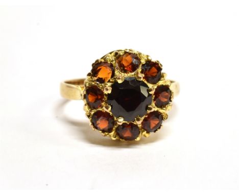 A GARNET ROUND CLUSTER 9 CARAT GOLD DRESS RING central round mixed cut red garnet 6mm diameter, shank marked 9CT, ring size M